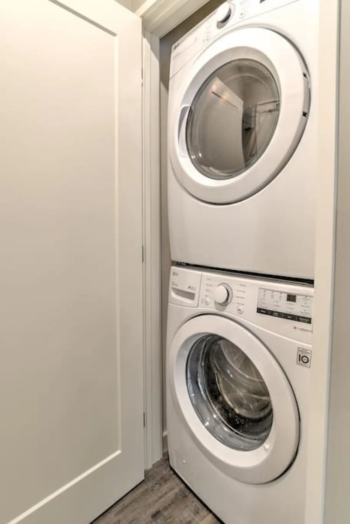 A laundry area featuring a stacked washer and dryer with white cabinetry, evoking a sense of convenience and practicality within a clean, organized space.