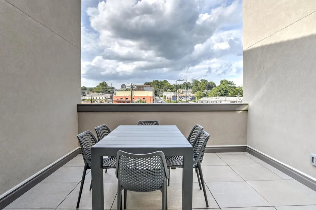 This exterior image captures an inviting rooftop terrace set for outdoor dining, with a contemporary table and chairs positioned to overlook sweeping southside city views beneath a cloudy sky. The airy setting is ideal for socializing, enjoying meals, or relaxing while taking in the urban panorama.