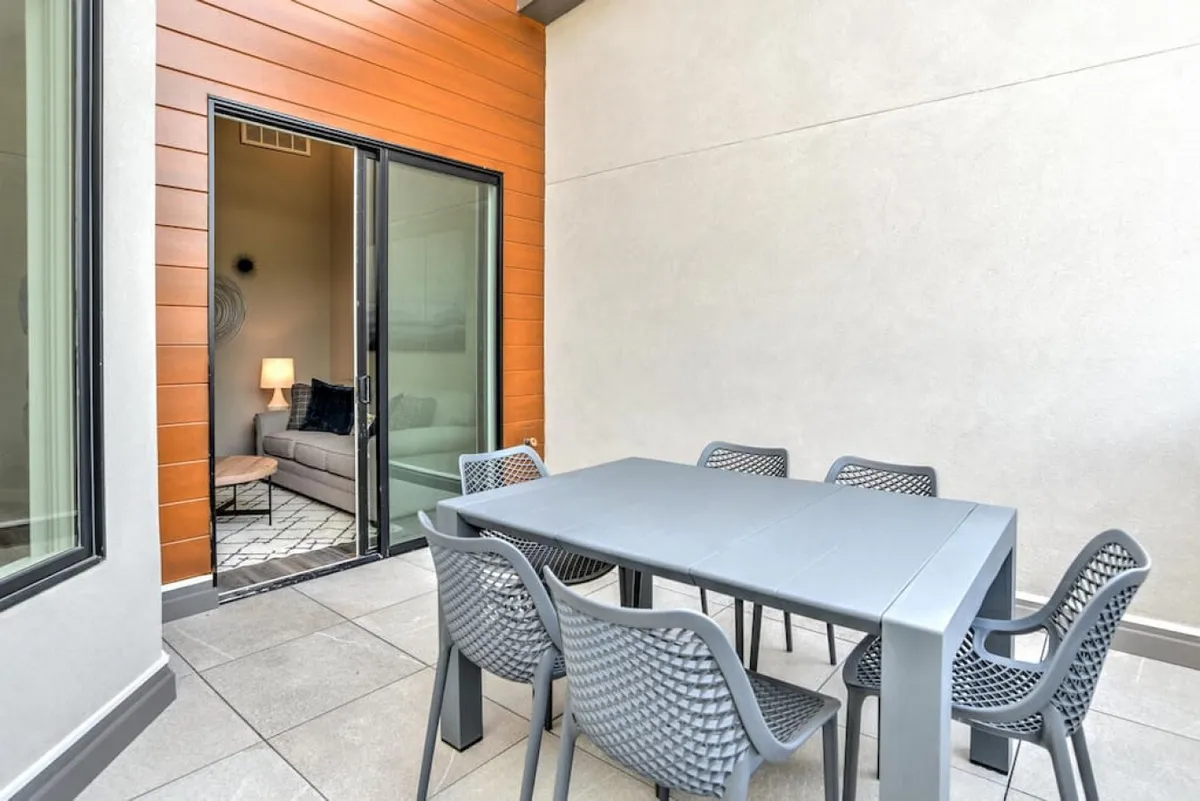 This image shows the seamless transition from an interior sitting area out onto an exterior rooftop deck. A glass door opens onto an al fresco dining space, with the interior living area visible, emphasizing the flow between indoor comfort and outdoor enjoyment.