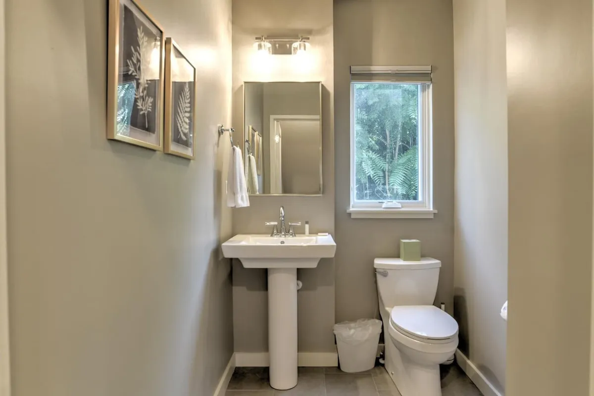 A compact and stylish half bath featuring a modern sink, toilet, and a window with natural light. The fixtures are sleek and the atmosphere is fresh and serene, making it a convenient spot for guests.